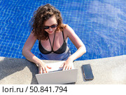 Top view freelancer traveler woman working remotely on computer at pool in luxury resort during her summer holiday. Work from anywhere, Technology and lifestyle concept, copy space. High quality photo. Стоковое фото, фотограф Ирина Михайличенко / Фотобанк Лори