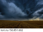 Dark storm clouds in an agricultural field in autumn. An impending storm, hurricane or thunderstorm. Стоковое фото, фотограф Емельянов Евгений Викторович / Фотобанк Лори
