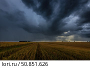 Dark storm clouds in an agricultural field in autumn. An impending storm, hurricane or thunderstorm. Стоковое фото, фотограф Емельянов Евгений Викторович / Фотобанк Лори