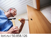 Creating precise mortise with chisel and hammer, installer shapes cavity inside door edge to fit lock mechanism as part of interior door renovation. Стоковое фото, фотограф Владимир Григорьев / Фотобанк Лори