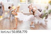 Man and his students perform hip hop dance on one bent leg, movement in horizontal plane near floor. Стоковое фото, фотограф Яков Филимонов / Фотобанк Лори