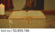 Bible and candle placed on a marble altar during service inside catholic church. Стоковое видео, видеограф Igor Tichonow / Фотобанк Лори