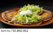 Three traditional Mexican sopes with refried beans, lettuce, and sour cream on a terracotta plate. Authentic latin american street food for menu design. Стоковое AI-изображение, AI-художник Анжелика Самсонова / Фотобанк Лори