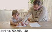 Dad teaches his son writing and counting. Kids primary education. Children learn, study in home school. Daddy male helping teaching little child boy support studying, learning homework. Knowledge day. Стоковое видео, видеограф Марина Демидюк / Фотобанк Лори