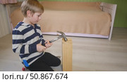 Kid hammers nails to wood with a hammer. Little boy helping with toy tools. Funny 6 years child having fun on building. Kid hammering crafting stuff using wooden pieces. Carpentry and family concept. Стоковое видео, видеограф Марина Демидюк / Фотобанк Лори