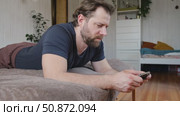 Man using his cellphone. Handsome guy use mobile phone at home. Male browses social networks, gaming, does shopping online, chats with friends, writes or reads messages. Close up. 4k video footage. Стоковое видео, видеограф Марина Демидюк / Фотобанк Лори