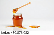 A glass jar filled with honey, with a wooden stirrer from which golden honey flows. Pools of honey form on the surface of the table, creating an appetizing and natural atmosphere. Стоковое AI-изображение, AI-художник Светлана  Громак / Фотобанк Лори