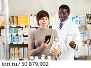 Woman buyer scans cream qr code with man pharmacist. Стоковое фото, фотограф Яков Филимонов / Фотобанк Лори
