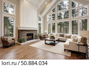 Elegant living room interior with vaulted ceiling and large windows showcasing forest view. Стоковое AI-изображение, AI-художник Иван Рябоконь / Фотобанк Лори