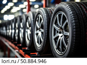 Car tires and alloy wheels showing rubber tread and metal rims in a storage facility. Стоковое AI-изображение, AI-художник Иван Рябоконь / Фотобанк Лори