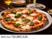 Delicious neapolitan pizza with fresh basil and cherry tomatoes on restaurant table. Стоковое AI-изображение, AI-художник Иван Рябоконь / Фотобанк Лори