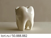 Big white shiny ceramic tooth resting on white surface. Стоковое AI-изображение, AI-художник Иван Рябоконь / Фотобанк Лори