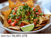 Delicious guacamole with tortilla chips and lime wedge in white bowl. Стоковое AI-изображение, AI-художник Иван Рябоконь / Фотобанк Лори