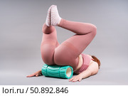 Fat woman in sportswear use myofascial release massage mfr roll on gray background, pelvic floor muscle exercise. Стоковое фото, фотограф Станислав Тарко / Фотобанк Лори