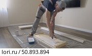 Man Professional carpenter painting wooden boards with white paint using roller brush in modern interior room during home renovation construction. Painting of wooden shelving. furniture assembly. Стоковое видео, видеограф Сергей Тимофеев / Фотобанк Лори