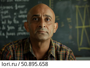 Balding professor posing in front of chalkboard with equations. Стоковое AI-изображение, AI-художник Иван Рябоконь / Фотобанк Лори