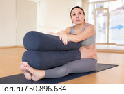 pregnant woman practices yoga with roll in hall. Стоковое фото, фотограф Татьяна Яцевич / Фотобанк Лори