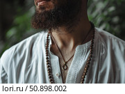 Guru wearing white shirt and wooden beads showing pendant necklace. Стоковое AI-изображение, AI-художник Иван Рябоконь / Фотобанк Лори