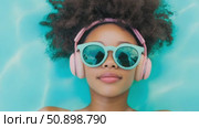 A tranquil overhead portrayal of a relaxed individual floating in clear aqua water, sporting chic eyewear and comfortable audio equipment. Стоковое AI-видео, аниматор Данила Большаков / Фотобанк Лори