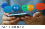 Person's hands interacting with a handheld computing device displaying an array of vibrant chat bubble symbols. Стоковое AI-видео, аниматор Данила Большаков / Фотобанк Лори
