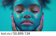 A person's serene countenance in a tranquil beauty ritual, featuring a radiant blue face covering with metallic and vibrant accents. Стоковое AI-видео, аниматор Данила Большаков / Фотобанк Лори
