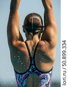 Diver preparing for springboard dive, showcasing athletic form and water splashes in the background. Стоковое AI-изображение, AI-художник Гайфуллина Дина / Фотобанк Лори