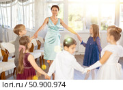 Smiling female teacher leading circle dance with group of tweens. Стоковое фото, фотограф Яков Филимонов / Фотобанк Лори