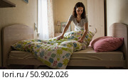 Woman making bed in cozy bedroom. Стоковое AI-изображение, AI-художник Ольга Невская / Фотобанк Лори