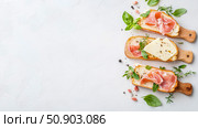 Gourmet appetizer concept: Slices of bread topped with cured meat and cheese, ideal for catering or a refined snack. Стоковое AI-изображение, AI-художник Данила Большаков / Фотобанк Лори