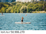 Teenage girl surfing on paddleboard on the lake in city. Редакционное фото, фотограф Константин Григорьев / Фотобанк Лори
