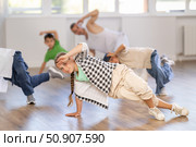 Smiling sports teen girl performing krump movements on floor with group children in breakdance studio with male coach. Стоковое фото, фотограф Яков Филимонов / Фотобанк Лори