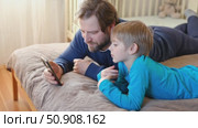 Father and son little boy laughing and using phone. They watching funny videos together, playing games on smartphone. Concept technology, smartphone addicted. Fun weekend activity. Modern fatherhood. Стоковое видео, видеограф Марина Демидюк / Фотобанк Лори