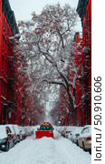 Winter scene: Snow plow clears a street lined with red buildings and snow-covered tree. Стоковое AI-изображение, AI-художник Данила Большаков / Фотобанк Лори