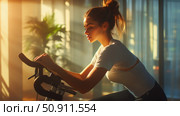 A young woman exercises on an exercise bike in a gym bathed in soft morning light. Concentration, calmness and energy are combined in this shot. Light sportswear emphasizes the dynamics and aesthetics of a healthy lifestyle. The atmosphere of coziness and silence speaks of personal self-care, inner discipline and strength. Perfect for the topics of fitness, yoga, motivation, healthy lifestyle and mindfulness. Стоковое AI-изображение, AI-художник Анна Кривицкая / Фотобанк Лори