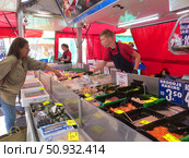 Городская ярмарка в центре города. Палатка с рыбой и морепродуктами. Продавец помогает покупательнице выбрать рыбу. Вагенинген. Нидерланды. Редакционное фото, фотограф Мария Фетисова / Фотобанк Лори