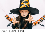 Happy funny child girl in witch costume on Halloween makes horror face and grimaces on white background. Halloween party girl. Happy Halloween Witch. High quality photo. Стоковое фото, фотограф Ирина Михайличенко / Фотобанк Лори