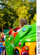 A little girl rides a green ride in a summer park. Russia. Moscow. 25.07.25. Редакционное фото, фотограф Ярославский Максим / Фотобанк Лори
