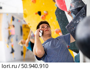 Man talking on mobile phone while exercising at artificial climbing wall. Стоковое фото, фотограф Яков Филимонов / Фотобанк Лори