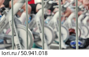 Athletes pedaling on exercise bikes during sports day behind a fence. Стоковое видео, видеограф Mikhail Davidovich / Фотобанк Лори