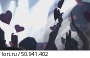Audience at concert holding heart-shaped signs with vibrant lights creating an energetic atmosphere. Стоковое видео, видеограф Данил Руденко / Фотобанк Лори