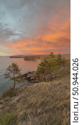 Vertical video of windy summer evening on the shore of Lake Baikal. View from Olkhon Island to Small Sea and pink clouds at sunset. Natural background with larches on rocky shore. Picturesque landscape. Стоковое видео, видеограф Виктория Катьянова / Фотобанк Лори