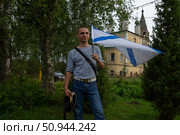 Мужчина, бывший моряк, с флагом в день ВМФ на улице Тутаева. Редакционное фото, фотограф Дмитрий Киселёв / Фотобанк Лори