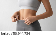 Fitness enthusiast adjusting workout outfit in minimalistic studio setting. Стоковое AI-изображение, AI-художник Katsiaryna Repich / Фотобанк Лори