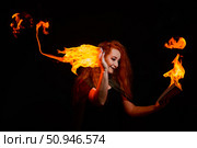 An ominous witch with long curly hair holds a magical fire. Tongues of flame on the palms of a red-haired smirking woman. Witchcraft. Стоковое фото, фотограф Михаил Решетников / Фотобанк Лори