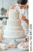 Pastry Art: Woman decorating an elegant tiered wedding cake with delicate frosting roses and ornate swirls for a sophisticated celebration. Стоковое AI-изображение, AI-художник Данила Большаков / Фотобанк Лори