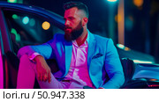 Man in blue suit sitting in a vehicle under neon lights, showcasing modern masculinity and sophistication in a nighttime setting. Стоковое AI-изображение, AI-художник Данила Большаков / Фотобанк Лори