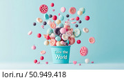 Sweet Delight: Conceptual still life of assorted confectioneries spilling from a vibrant blue container with text, set against a light blue surface. Стоковое AI-изображение, AI-художник Данила Большаков / Фотобанк Лори