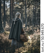 Viking cloak, basket, nature, braid, historical, blonde, walking, medieval, woods, and wilderness inspire this moody scene. Great for folklore, history, or outdoor living themes. A timeless glimpse. Стоковое AI-изображение, AI-художник Александра Троицкая / Фотобанк Лори