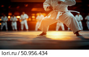 Dynamic low angle perspective of a martial arts practitioner in a white uniform executing a powerful stance on a reflective floor, illuminated by warm golden light, illustrating discipline and traini. Стоковое AI-изображение, AI-художник Данила Большаков / Фотобанк Лори