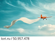 A vintage-style small aircraft flies gracefully, towing a large empty white banner across the sky. The charming scene showcases the nostalgia of classic aviation and aerial advertising. Стоковое AI-изображение, AI-художник Nart / Фотобанк Лори